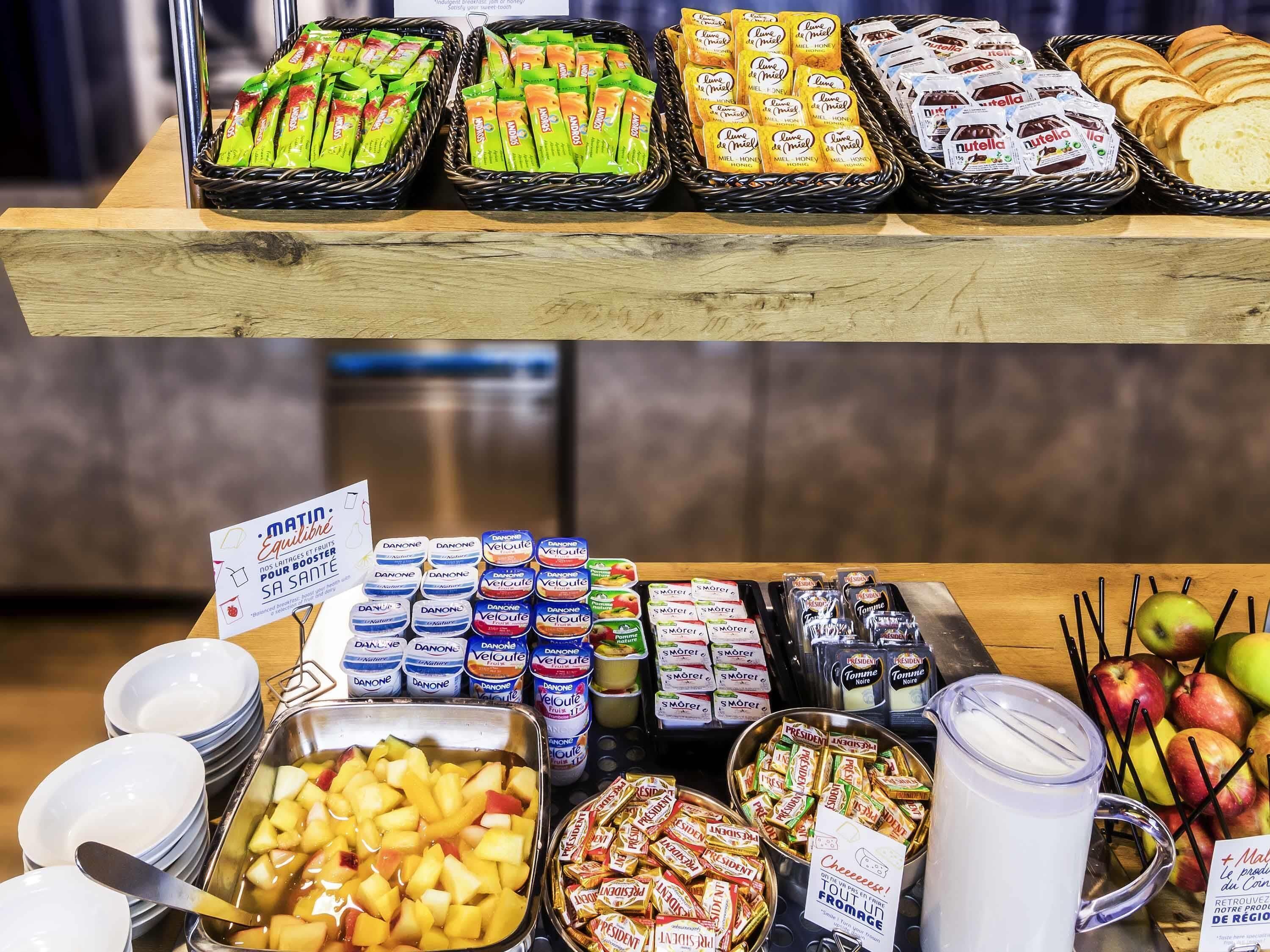 Un bufé con diversas opciones de comida, como frutas, quesos y aperitivos empaquetados.