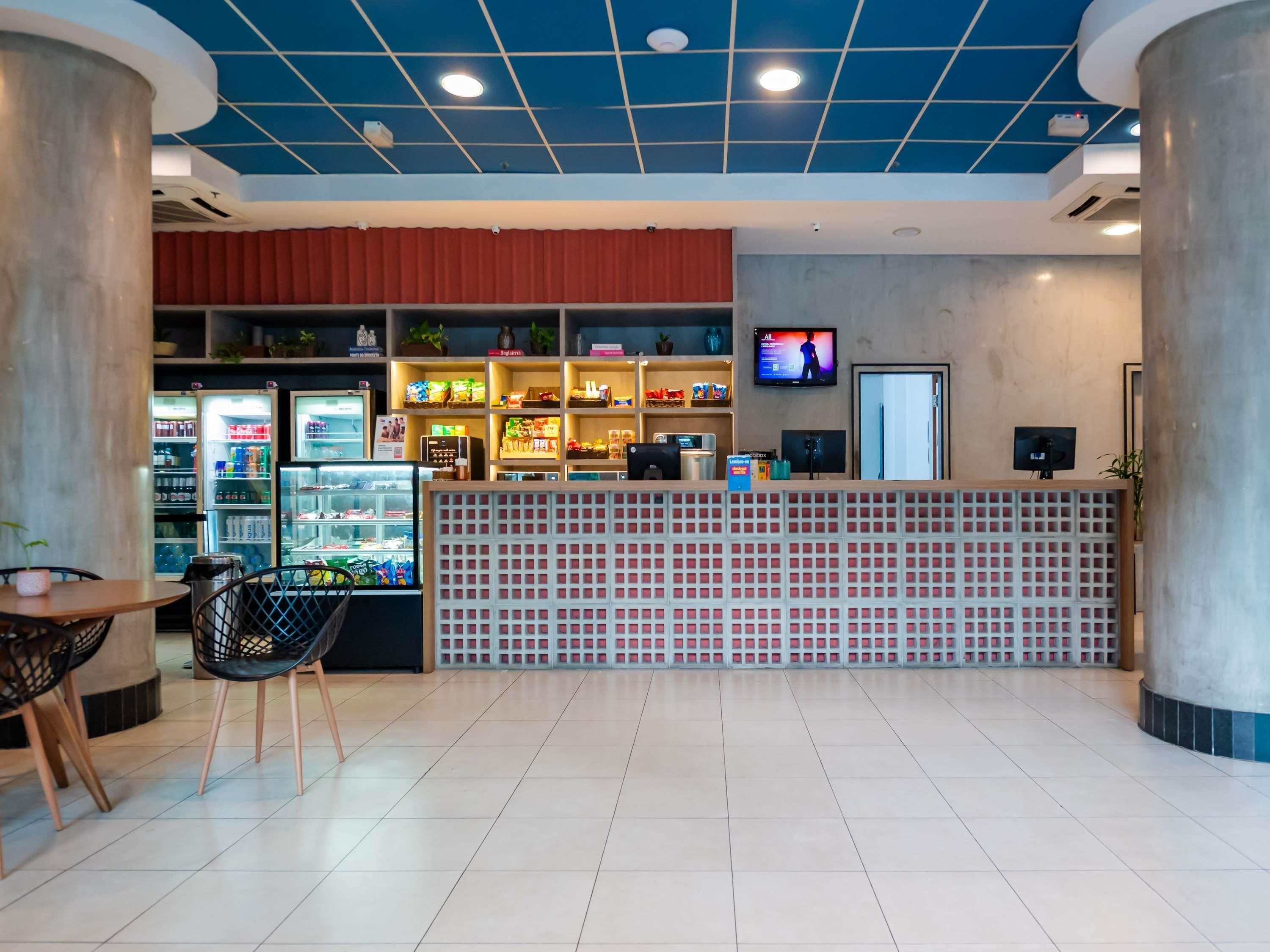 A modern interior with a reception desk, seating area, and a variety of food and beverage options.