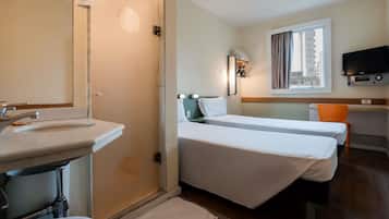Habitación de hotel con baño, cama, escritorio y televisor.