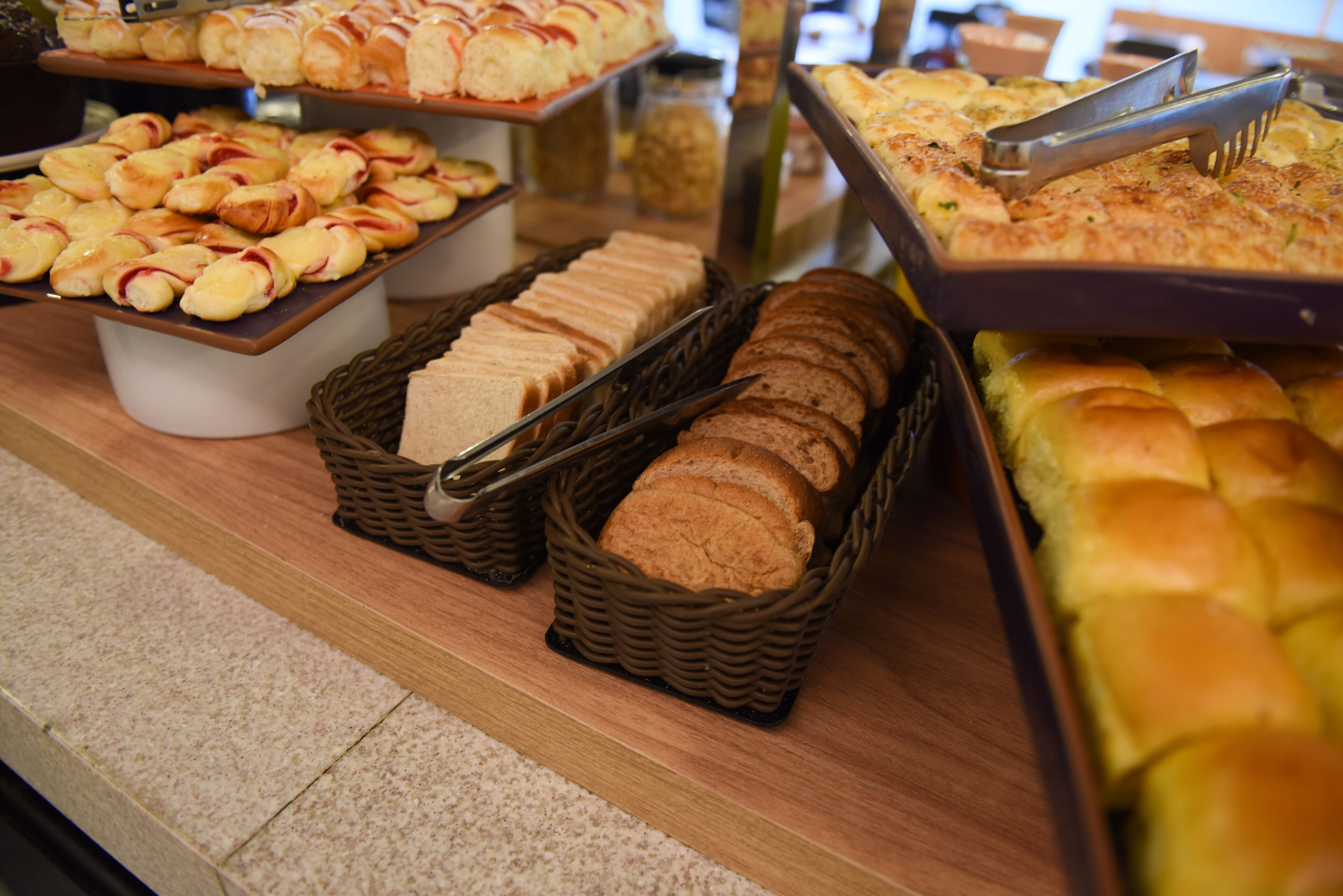 A buffet with various breads and pastries.