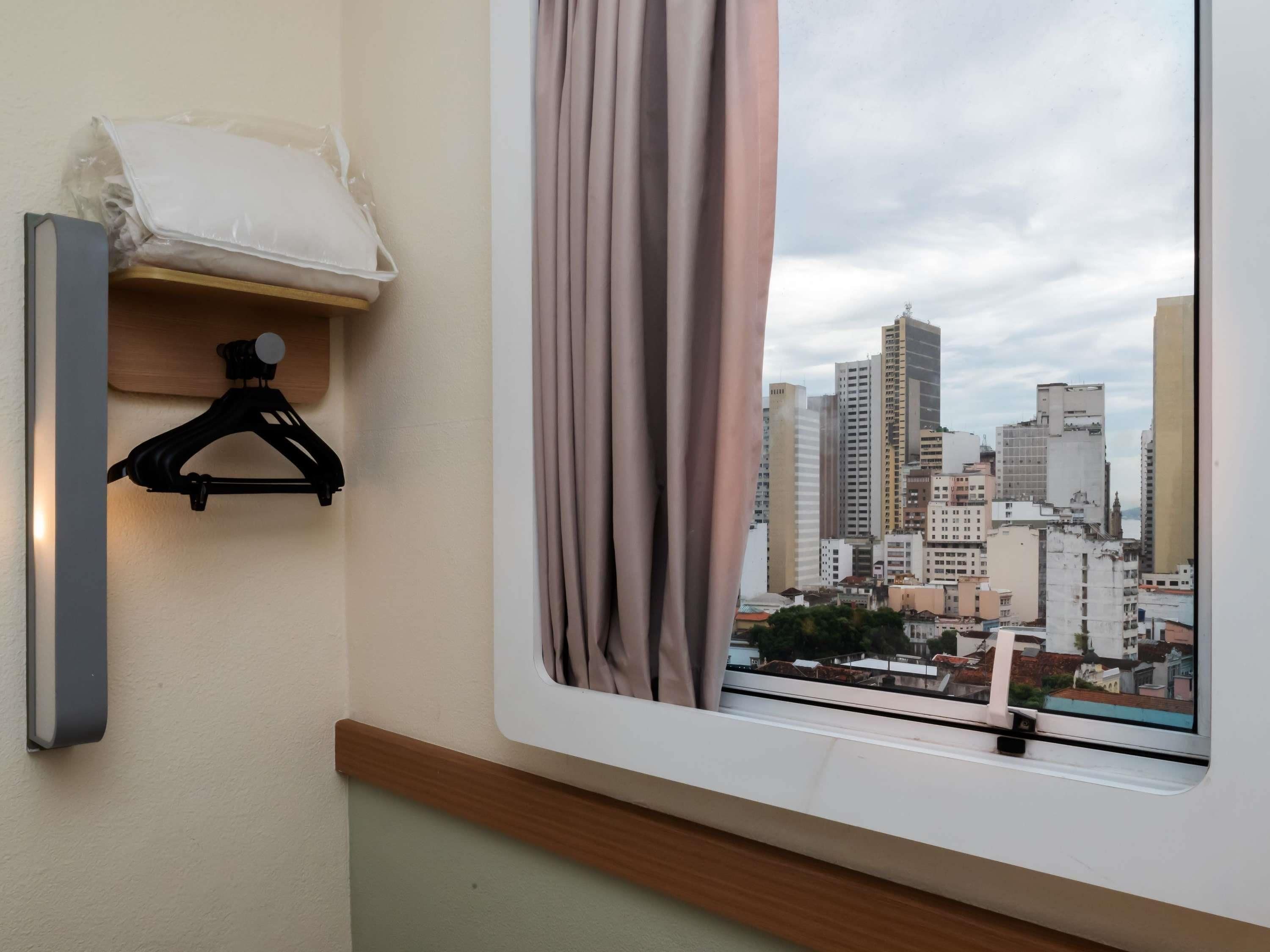 A room with a window, a black hanger, and a white pillow on a shelf.