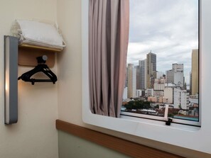 A room with a window, a black hanger, and a white pillow on a shelf. - ibis budget Rio de Janeiro Centro (Rio de Janeiro)
