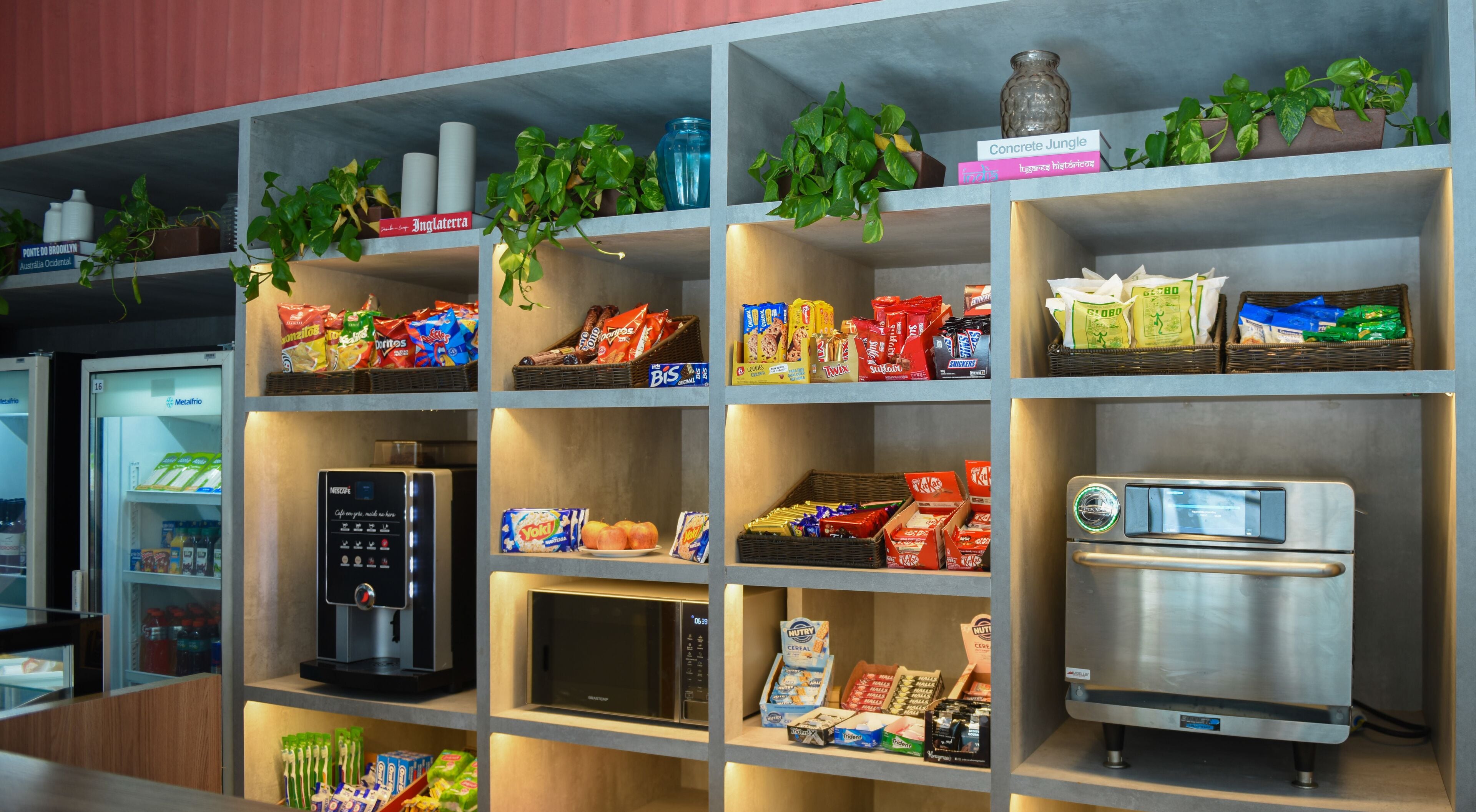 A snack and beverage display with various packaged goods, a coffee machine, and a bread machine.