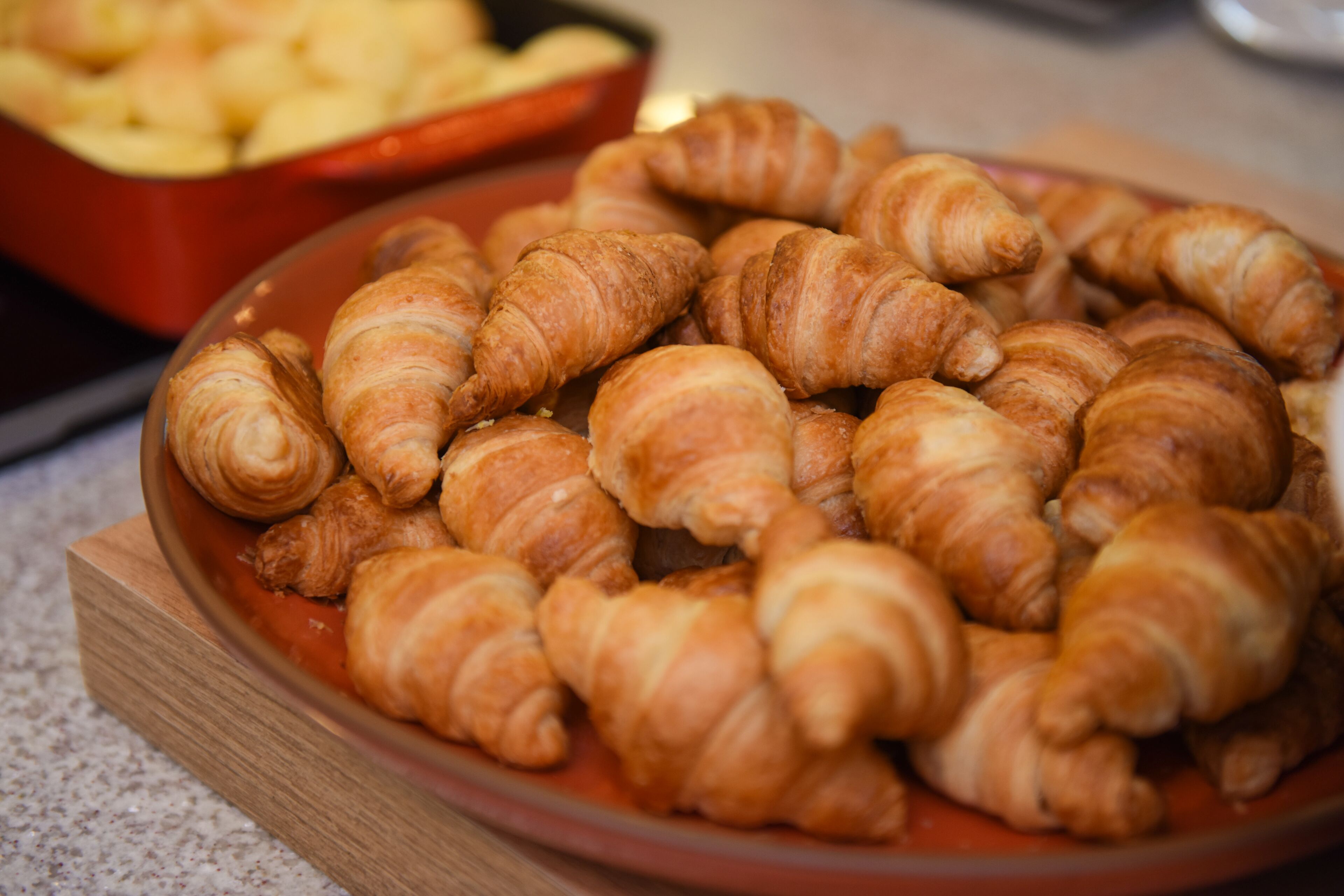 A wooden board with a plate of croissants.