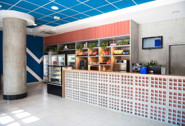 A modern reception area with a counter, refrigerated display cases, and shelves with snacks and plants. - ibis budget Rio de Janeiro Centro (Rio de Janeiro)