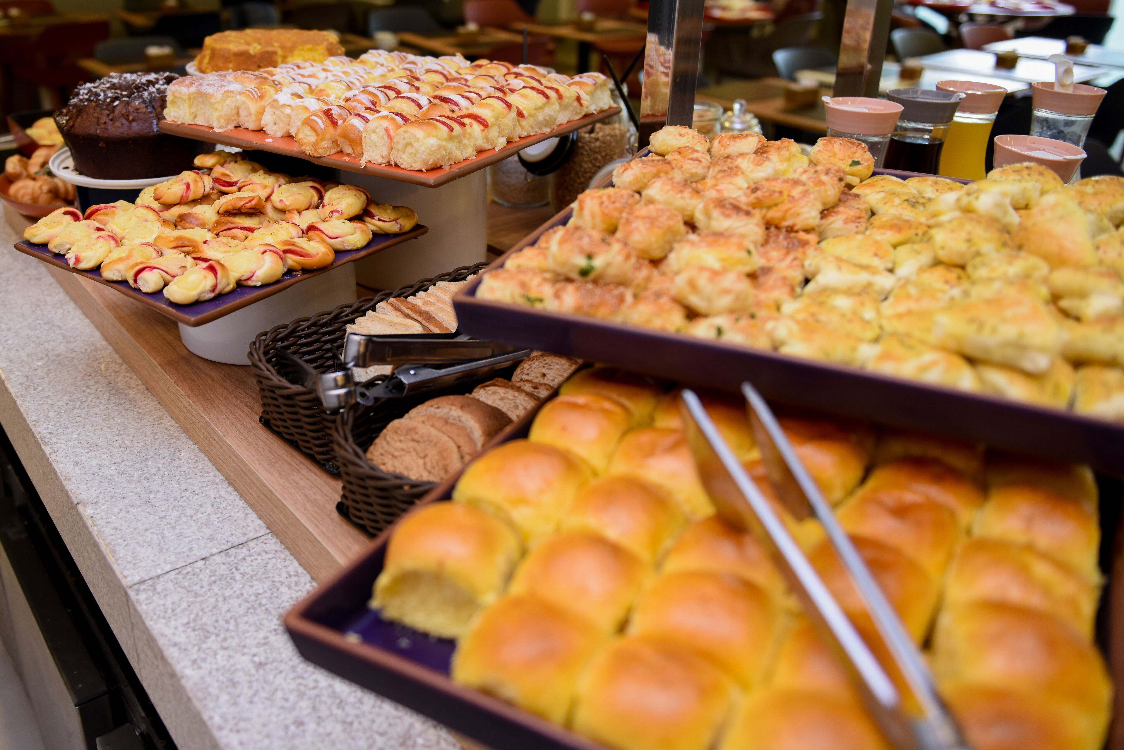 A buffet with various baked goods including pastries, muffins, and bread.