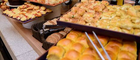 A buffet with various baked goods including pastries, muffins, and bread.