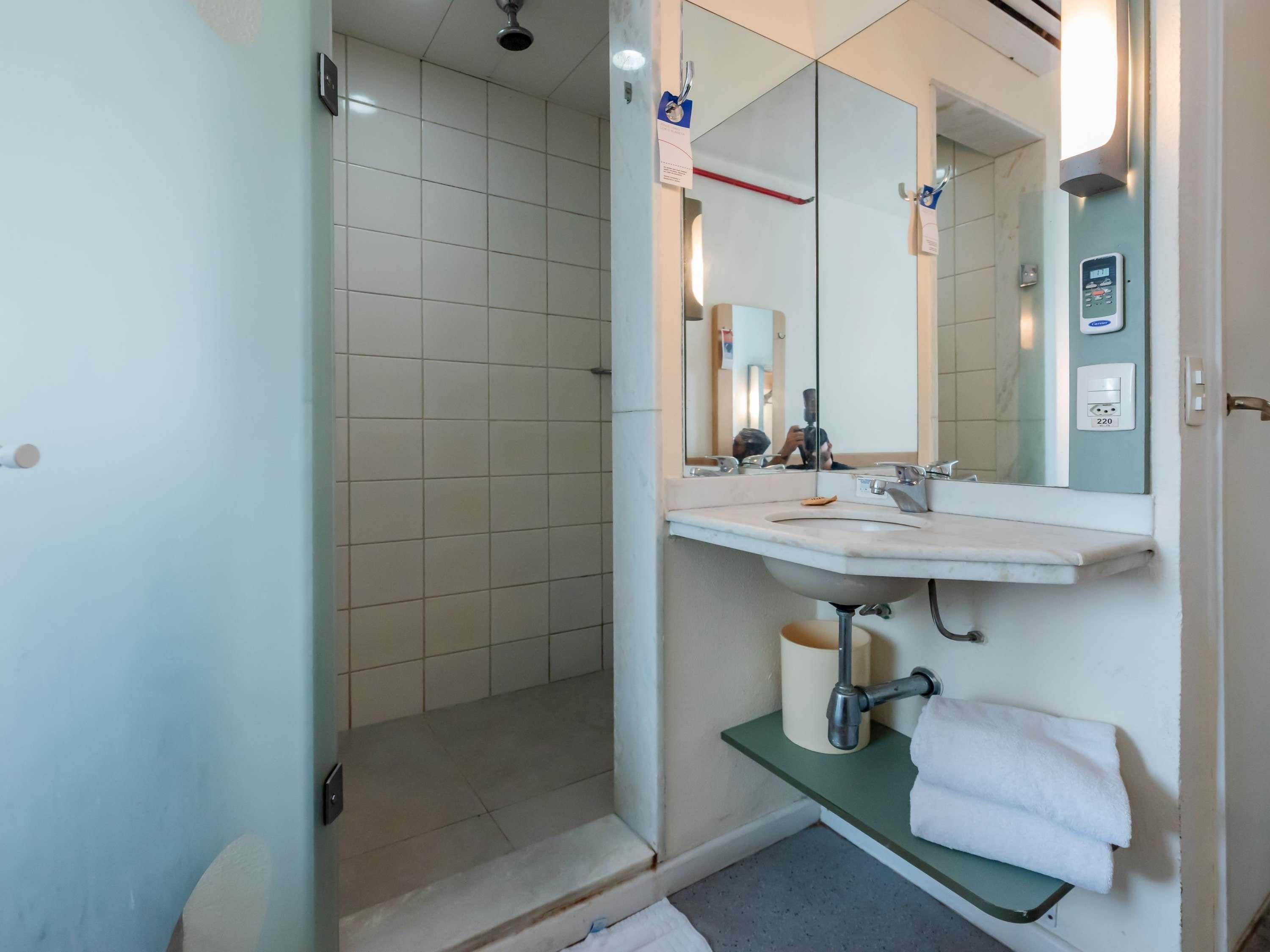 A bathroom with a shower, a sink, a mirror, and a towel rack.