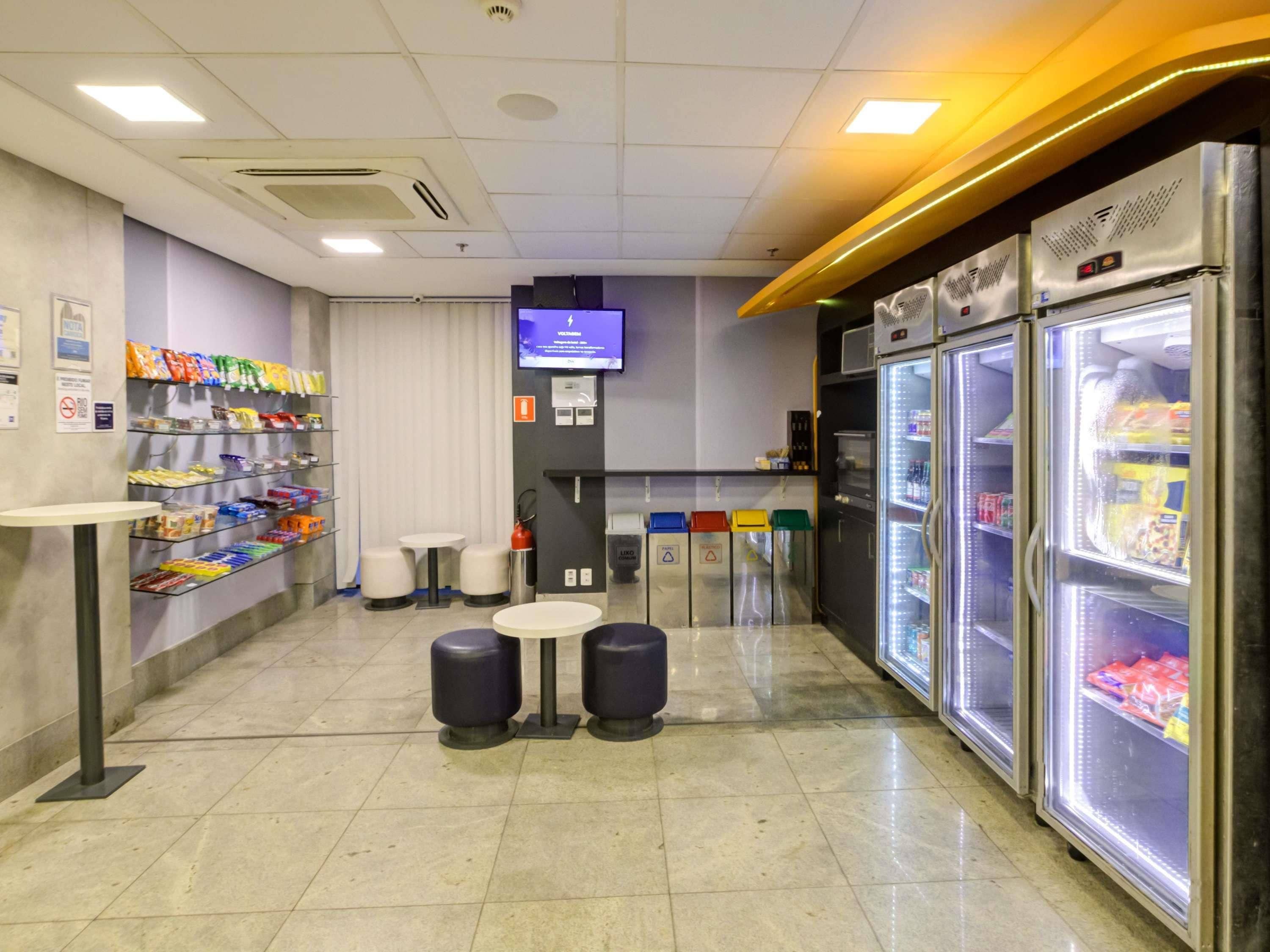 Un bar à collations propre et bien éclairé, avec des étagères remplies de snacks, un téléviseur et un réfrigérateur.