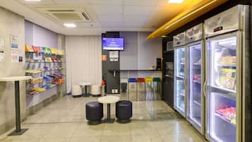 Un bar à collations propre et bien éclairé, avec des étagères remplies de snacks, un téléviseur et un réfrigérateur.