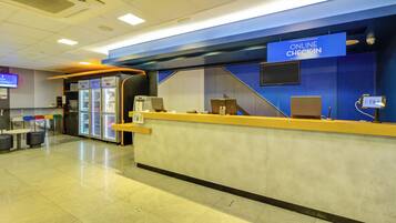 A check-in counter with an 'ONLINE CHECK-IN' sign, a seating area with chairs, and a refrigerator.