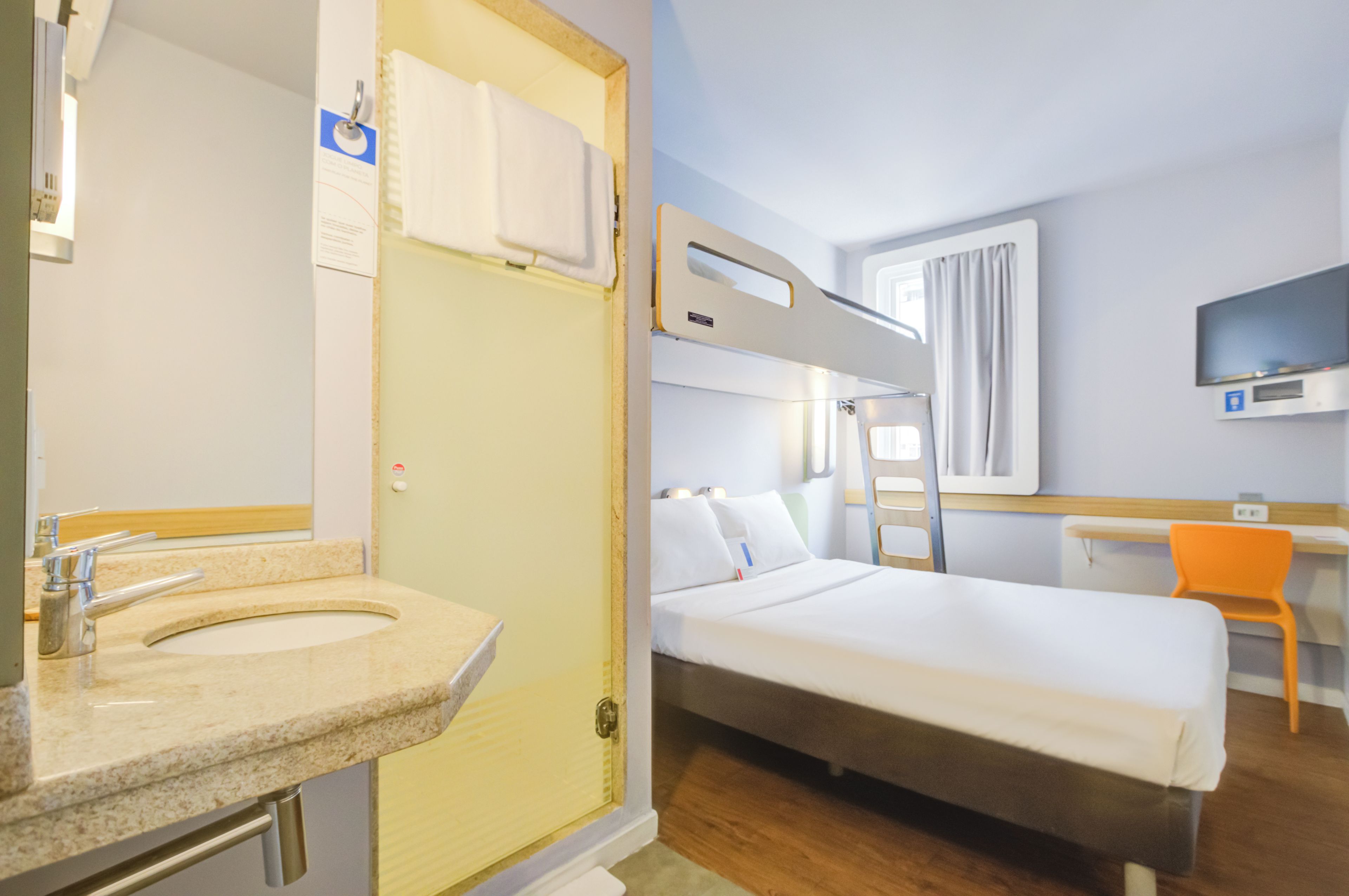 Une chambre d’hôtel équipée d’un lit, d’un bureau, d’une télévision et d’une salle de bain avec un lavabo et un miroir.