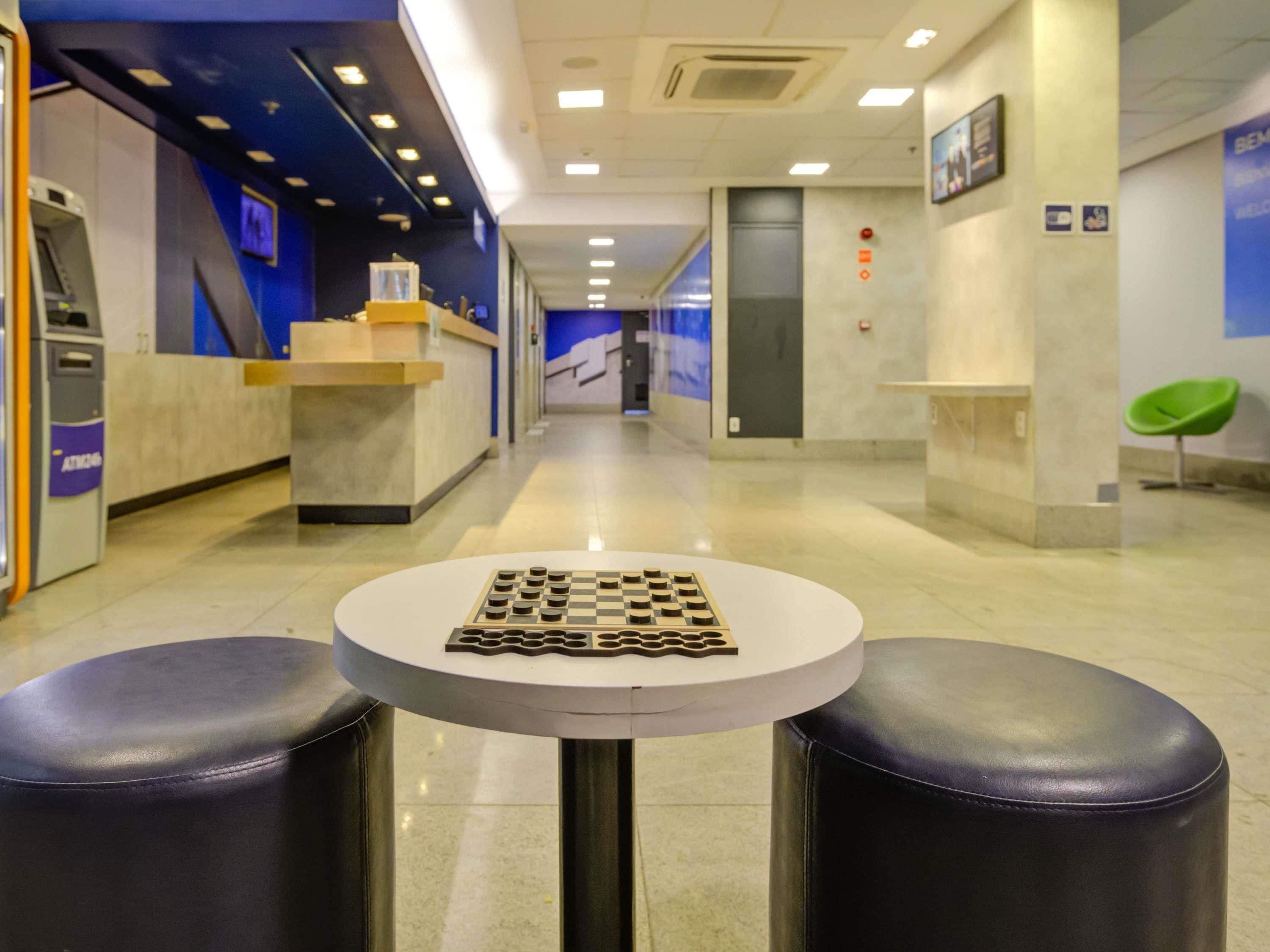 A modern hotel lobby with a chess table, leather seating, and a reception desk.
