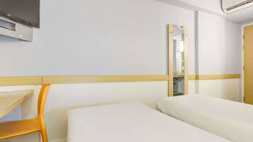 Una habitación de hotel con una cama, una silla, un televisor y un espejo.