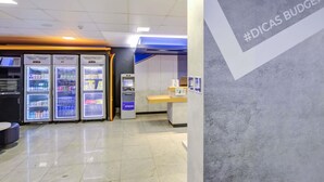A clean, modern interior with vending machines, a cash register, and a wall with '#DICAS BUDGET' text. - ibis budget Rj Copacabana (Rio de Janeiro)
