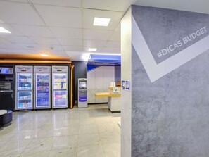 A clean, modern interior with vending machines, a cash register, and a wall with '#DICAS BUDGET' text. - ibis budget Rj Copacabana (Rio de Janeiro)