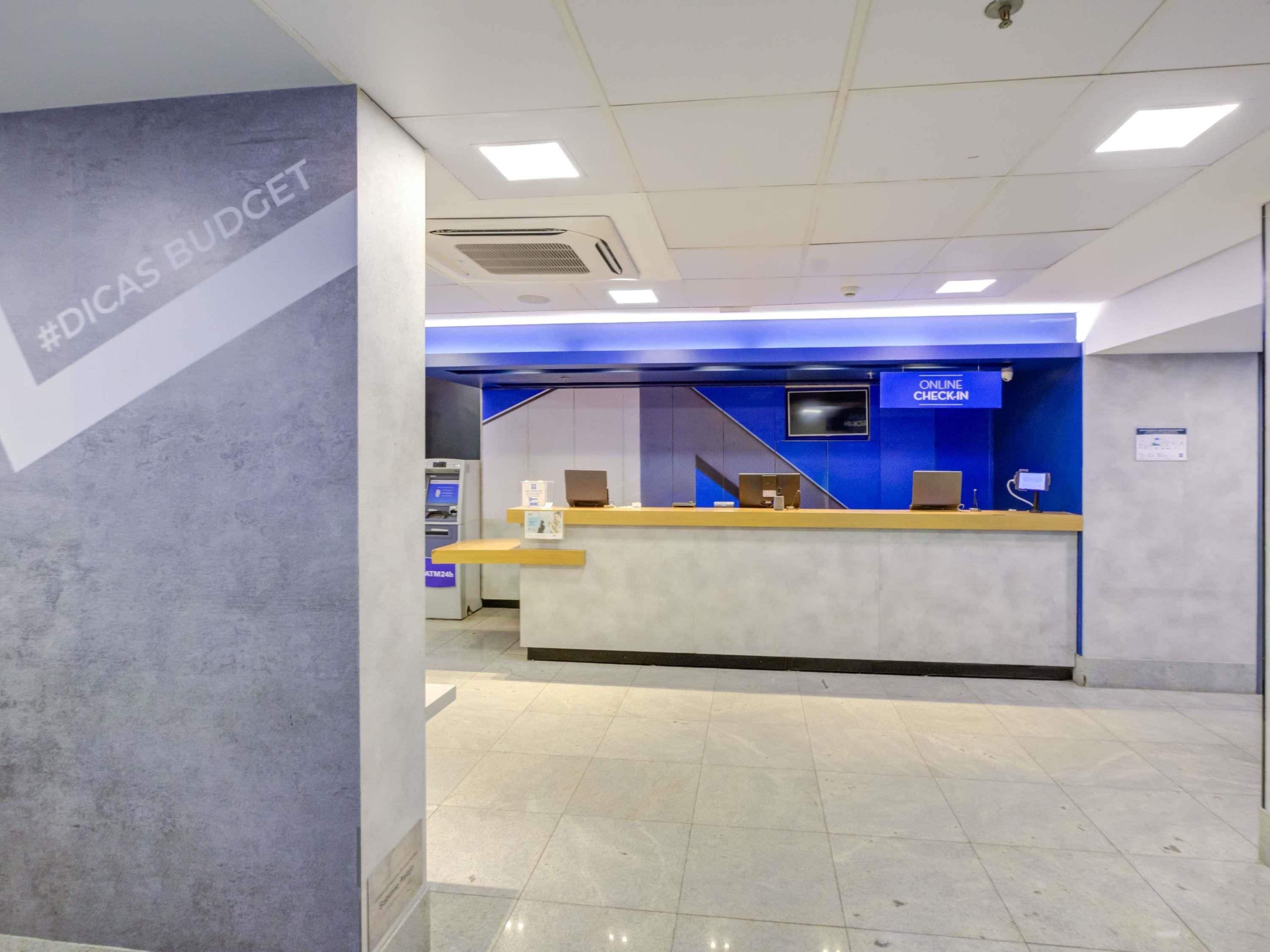 Una moderna reception con una parete azzurra, un bancomat e un cartello che indica il check-in online.