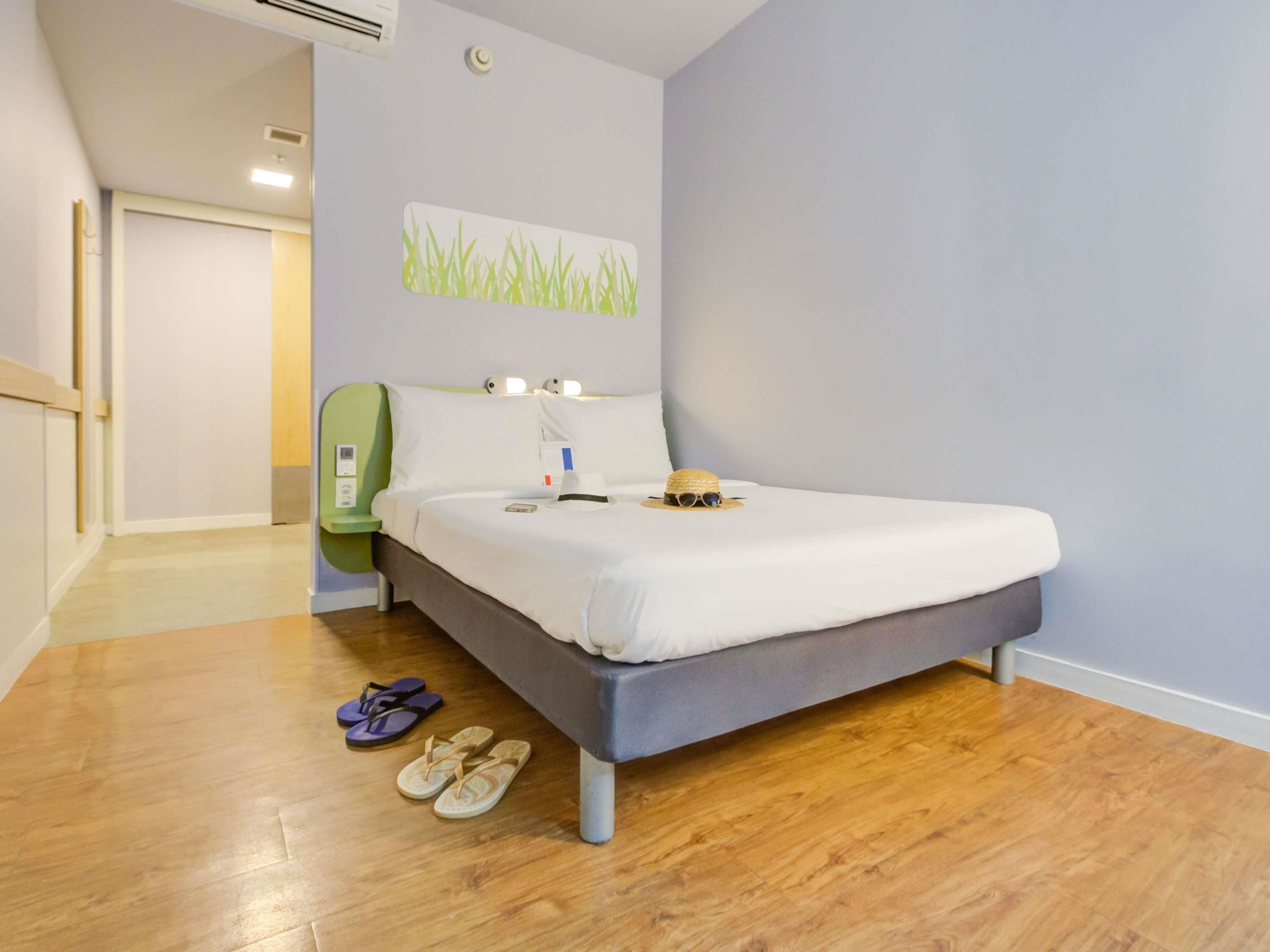 Habitación de hotel con cama, mesita de noche y aire acondicionado de pared.