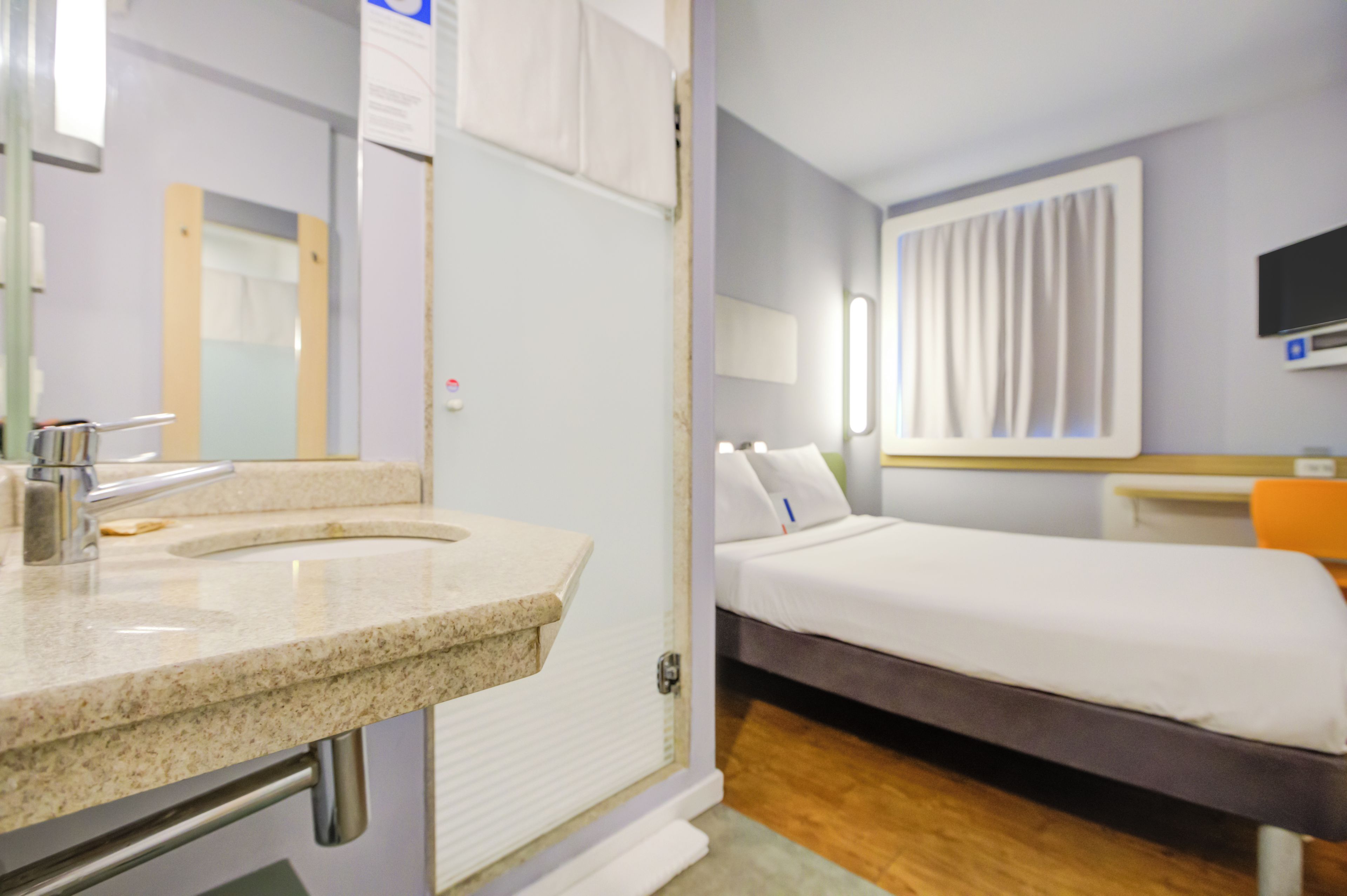 Una habitación de hotel con baño, cama y televisión.