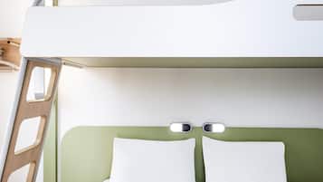 A bunk bed with a green headboard, white bedding, and a small bedside table with a bottle and sunglasses.