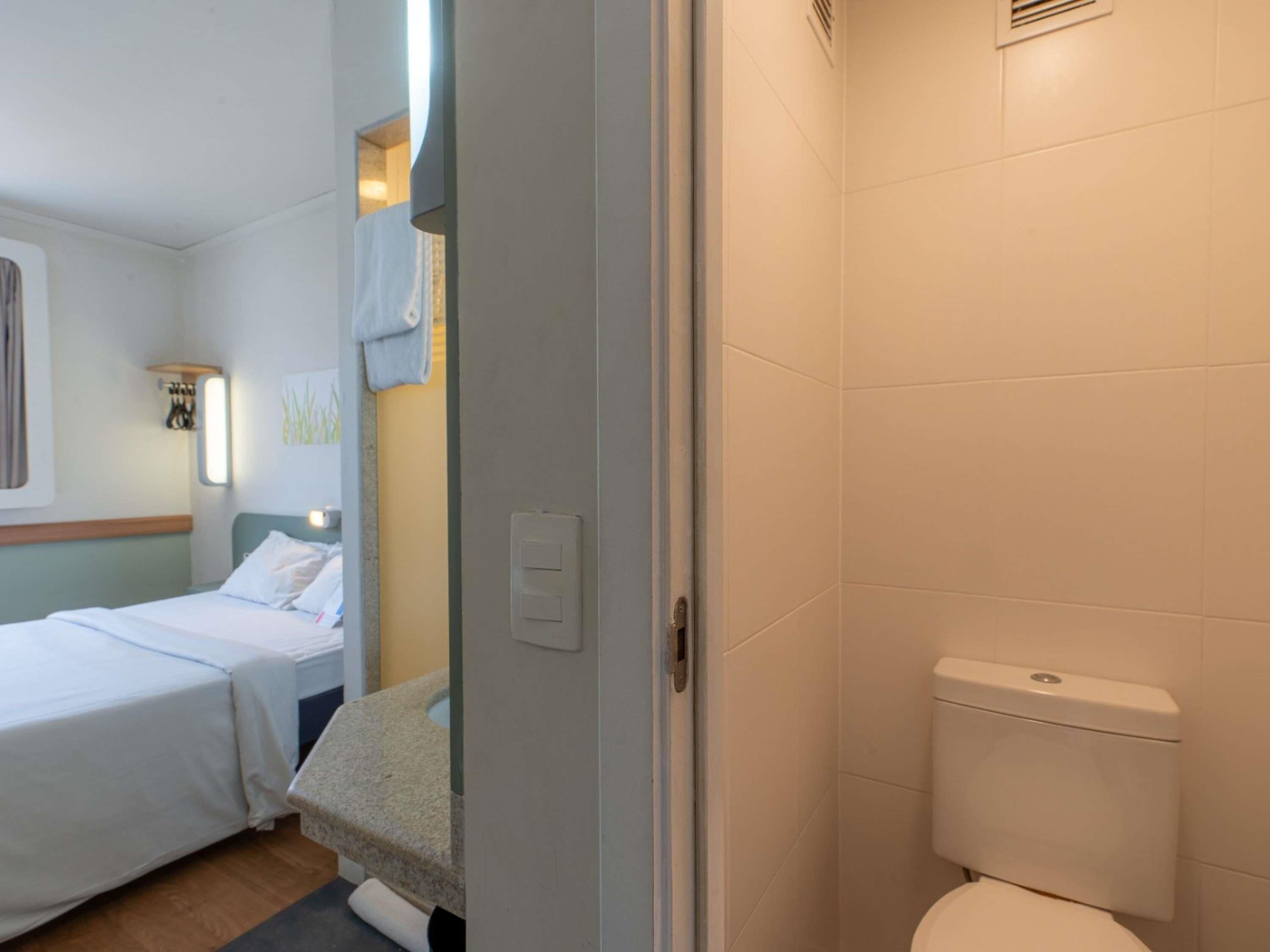 A hotel room with a bed, a bathroom with a toilet, and a shower area.