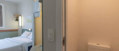 A hotel room with a bed, a bathroom with a toilet, and a shower area.
