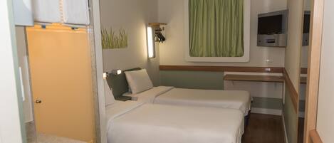 A hotel room with two beds, a small bathroom, a TV, and a green curtain.