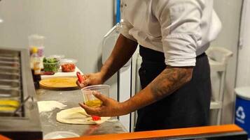 Un chef prepara comida en una cocina con mostrador negro y un atril para el menú.