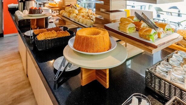 Un buffet proposant une variété de plats, notamment des gâteaux, des pâtisseries et des sandwichs, présentés sur des présentoirs et des plateaux en bois.