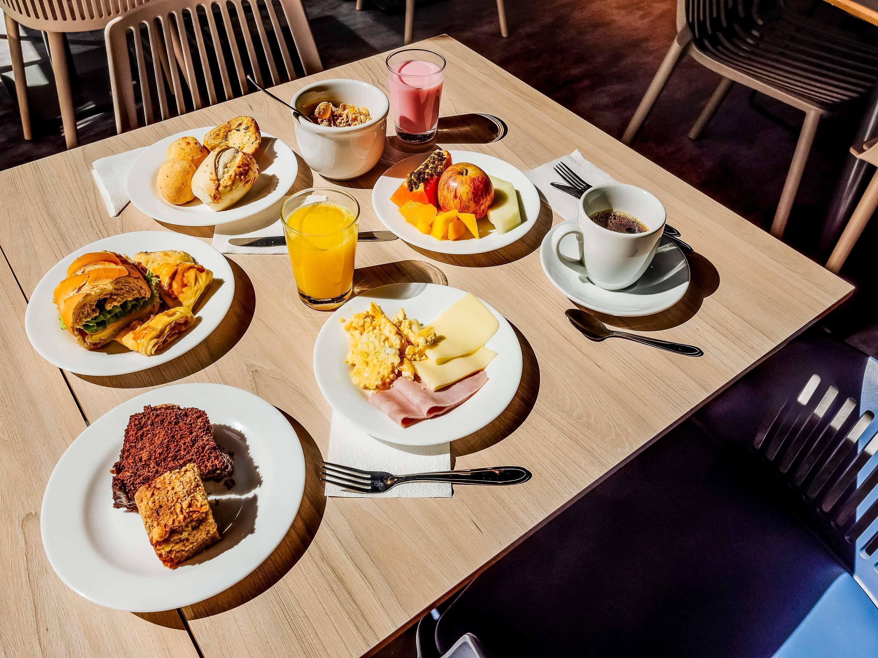 A breakfast table with various dishes, a glass of orange juice, and a cup of coffee.