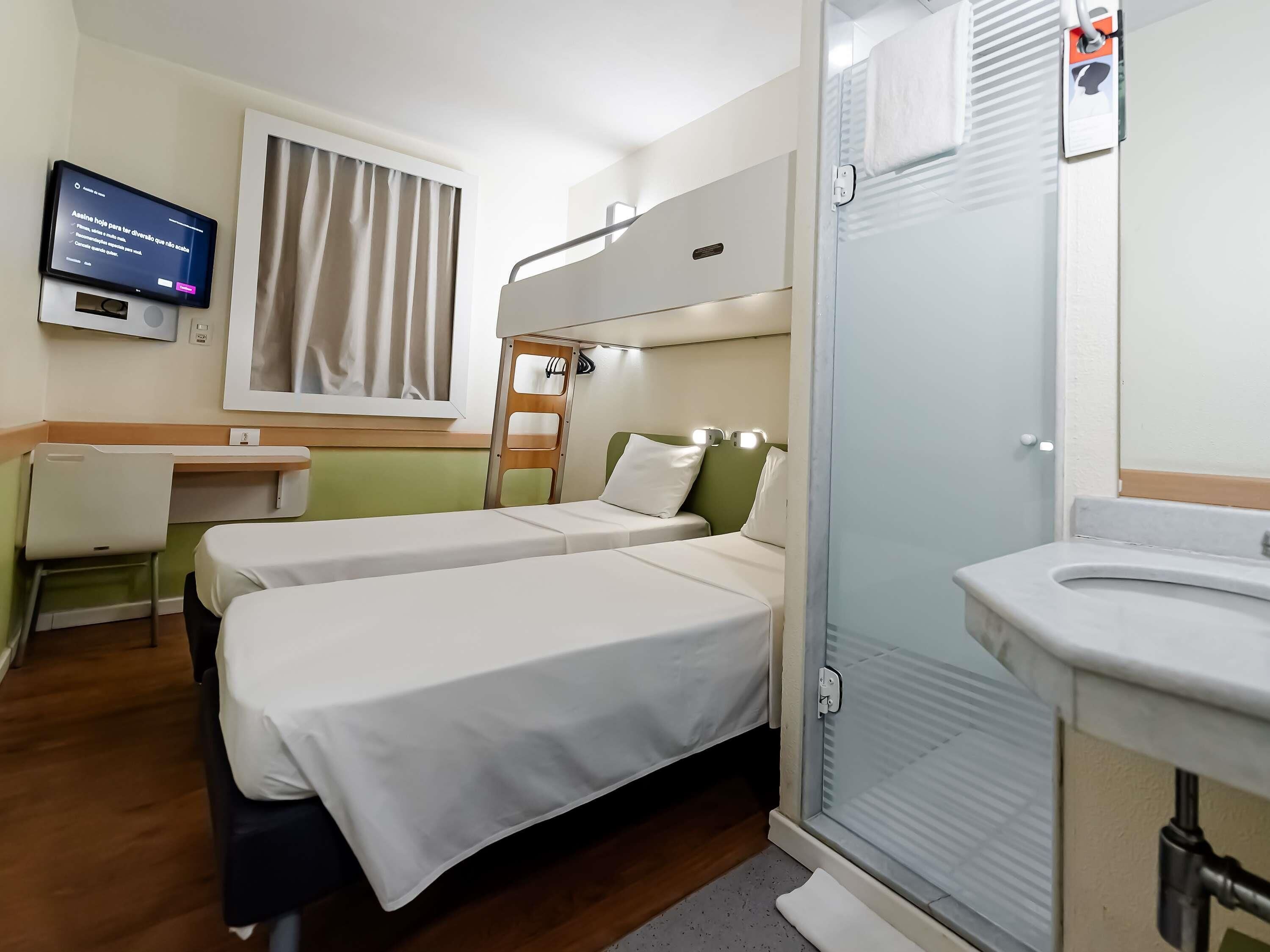 Habitación de hotel con dos camas, un escritorio, televisor y baño.