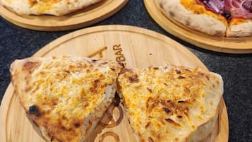 Three pizzas on wooden boards with a kitchen counter in the background.