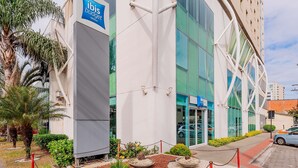 Un bâtiment d'hôtel moderne, avec une enseigne « ibis budget » bien visible, de grandes fenêtres et un espace paysager aménagé en jardin.