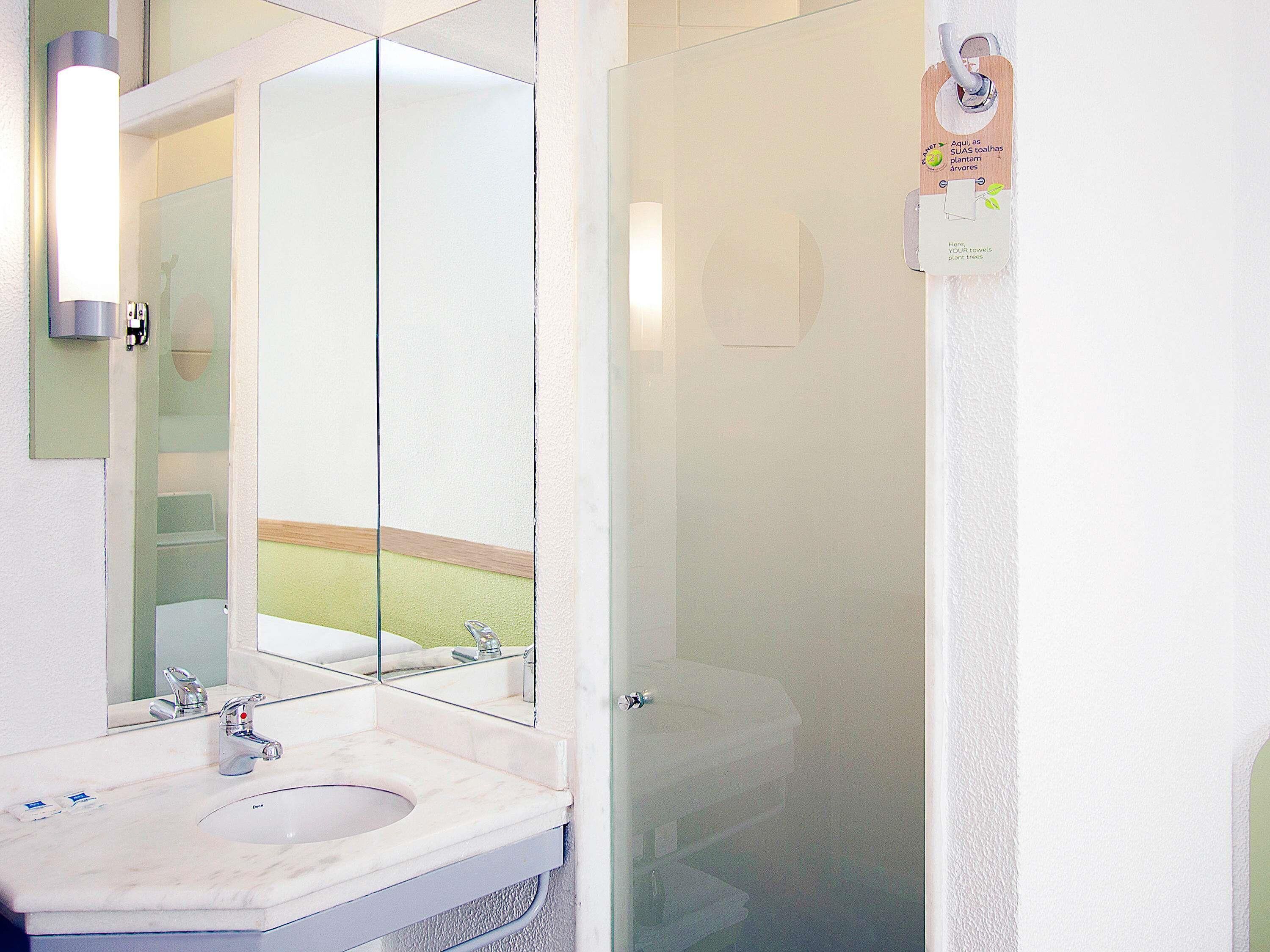 A bathroom with a sink, mirror, and glass shower door.