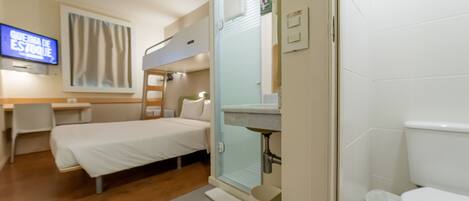 A hotel room with a bed, a desk, a television, and a bathroom.