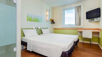Quarto de hotel com duas camas, uma escrivaninha, televisão e janela com cortinas.