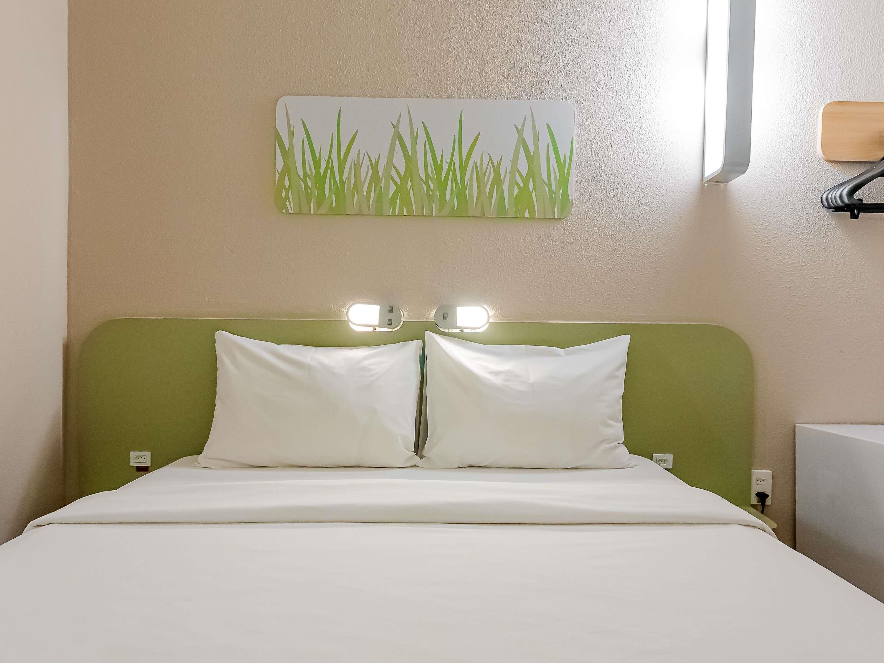 A bed with white bedding, a green headboard, and two bedside lamps.