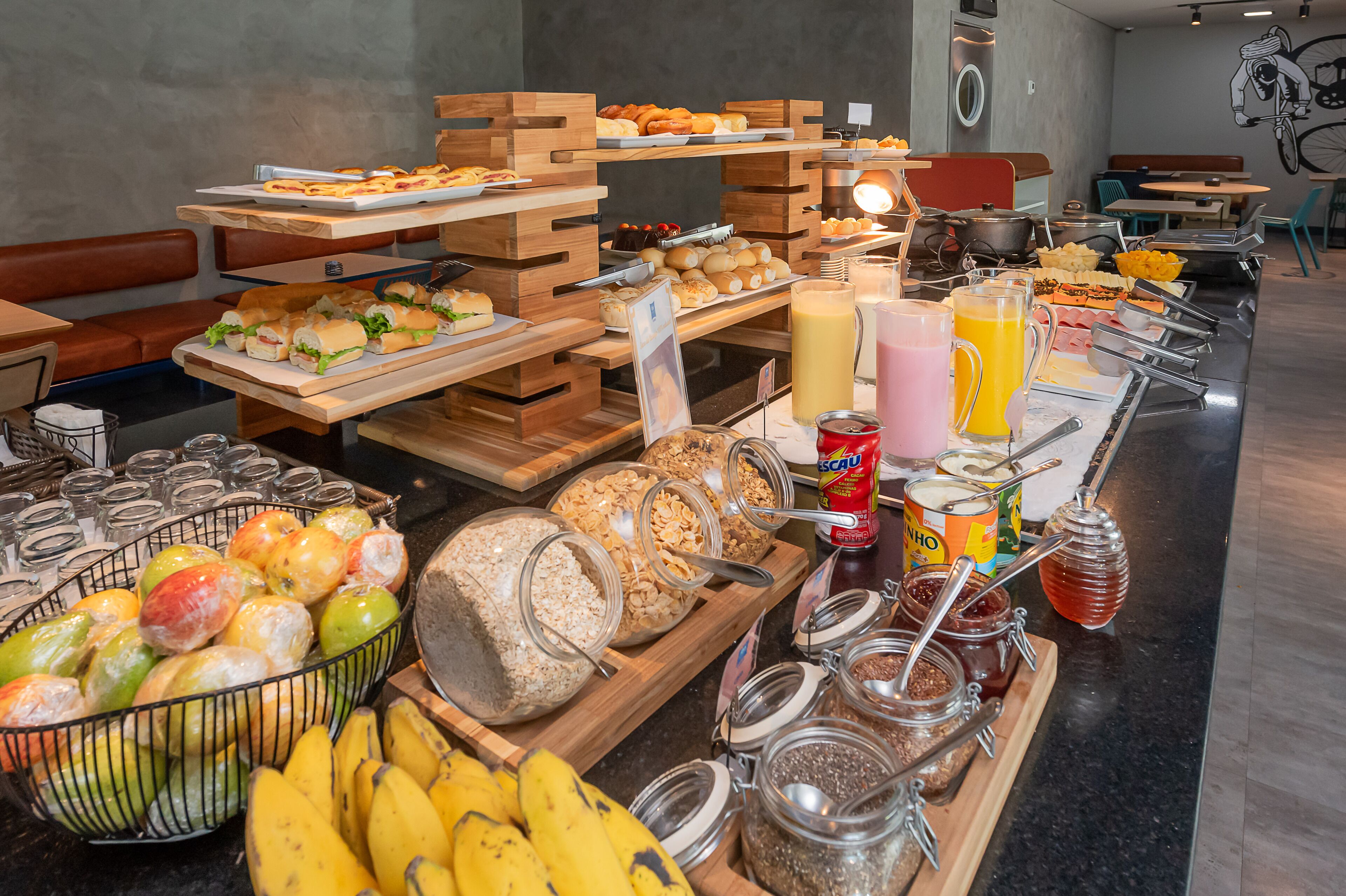 A buffet with various food items and beverages, including fruits, sandwiches, and juices.
