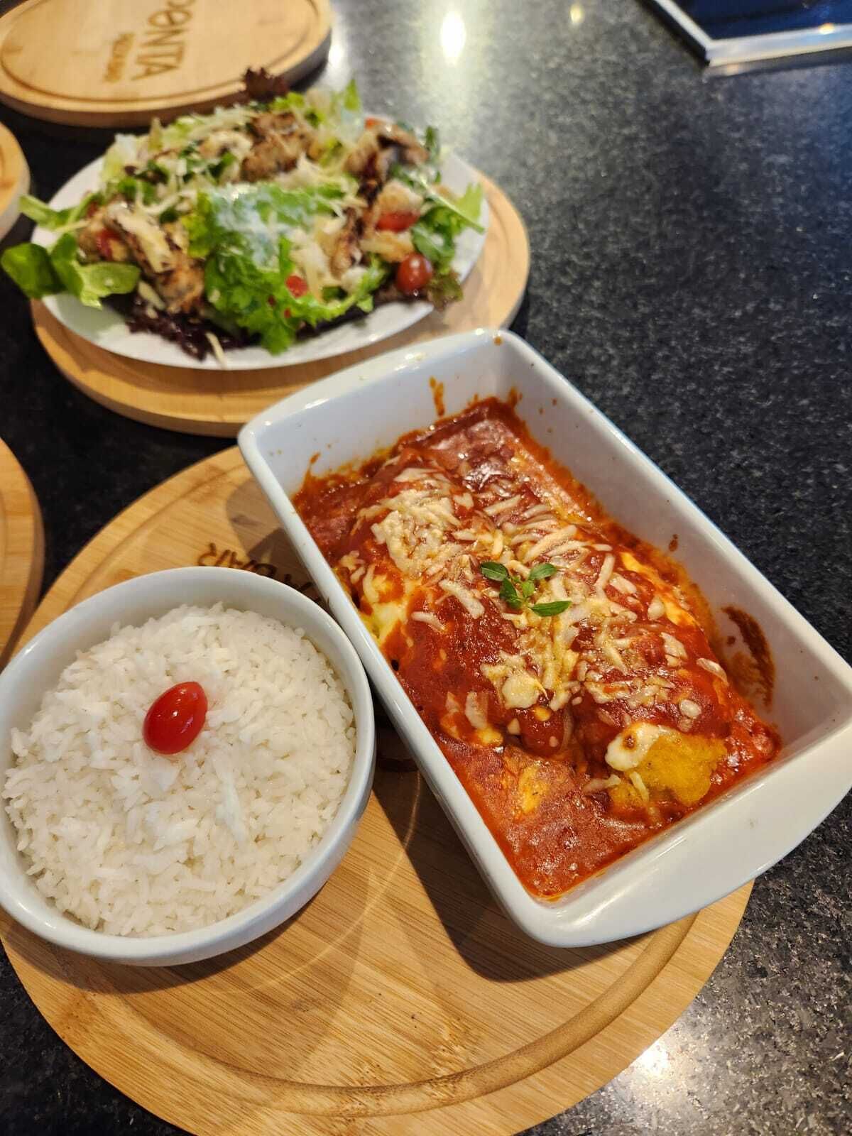 A meal with pasta, rice, and a salad on a wooden board.
