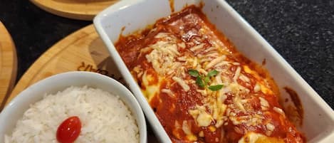 A meal with pasta, rice, and a salad on a wooden board.