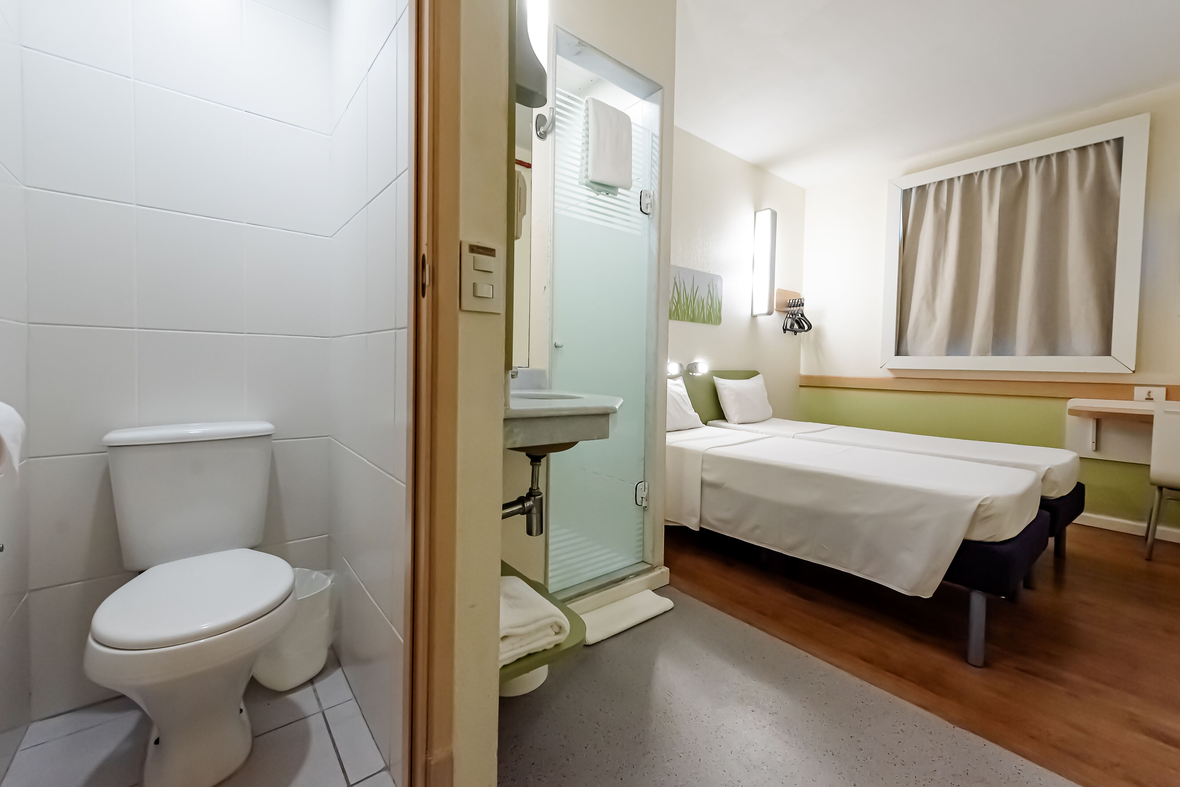 Habitación de hotel con inodoro, lavabo y cama.