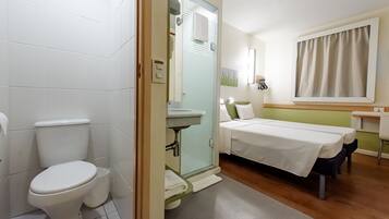 Habitación de hotel con inodoro, lavabo y cama.