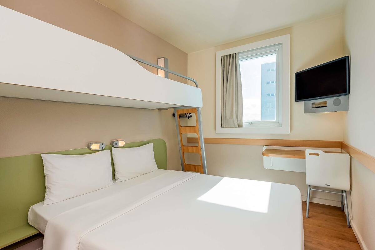 A bunk bed with a desk and a TV in a hotel room.