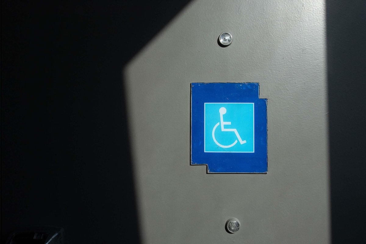 A blue wheelchair accessibility sign on a metallic surface.