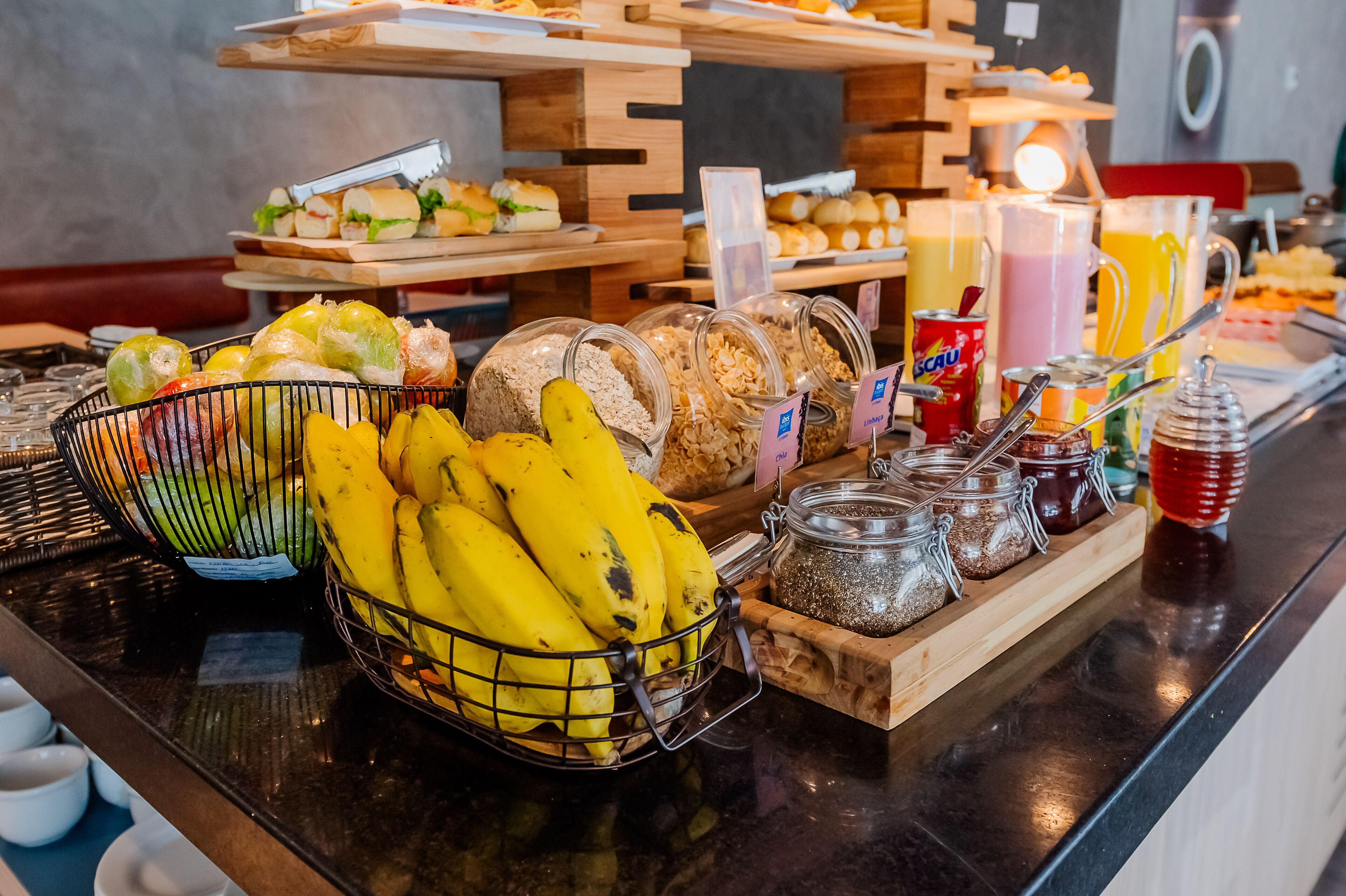 Un bufé con diversas opciones de comida, incluyendo frutas, panes y bebidas.