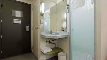 Un baño con lavamanos, espejo, toallero y una puerta con cerradura.