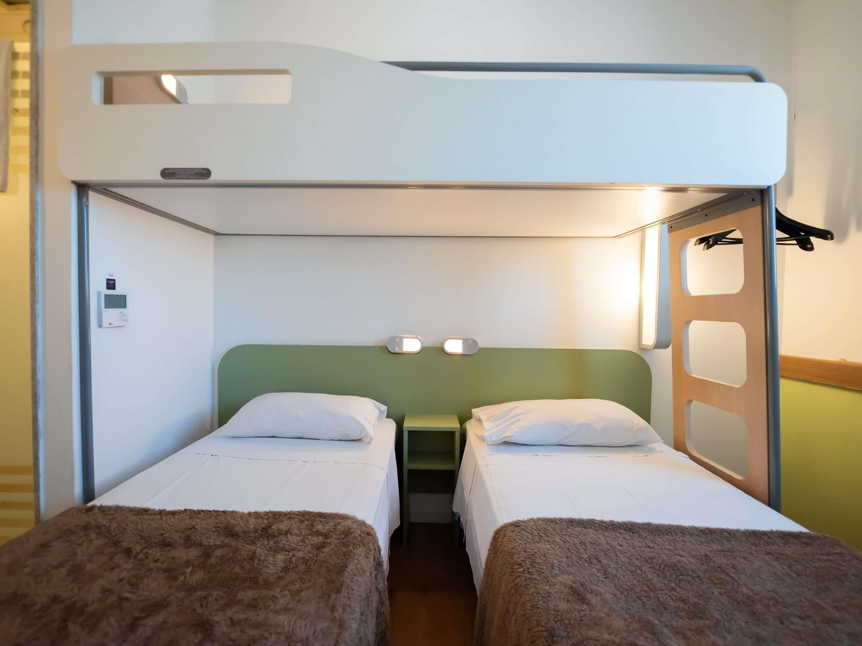 A bunk bed room with two beds, a control panel, and a coat rack.