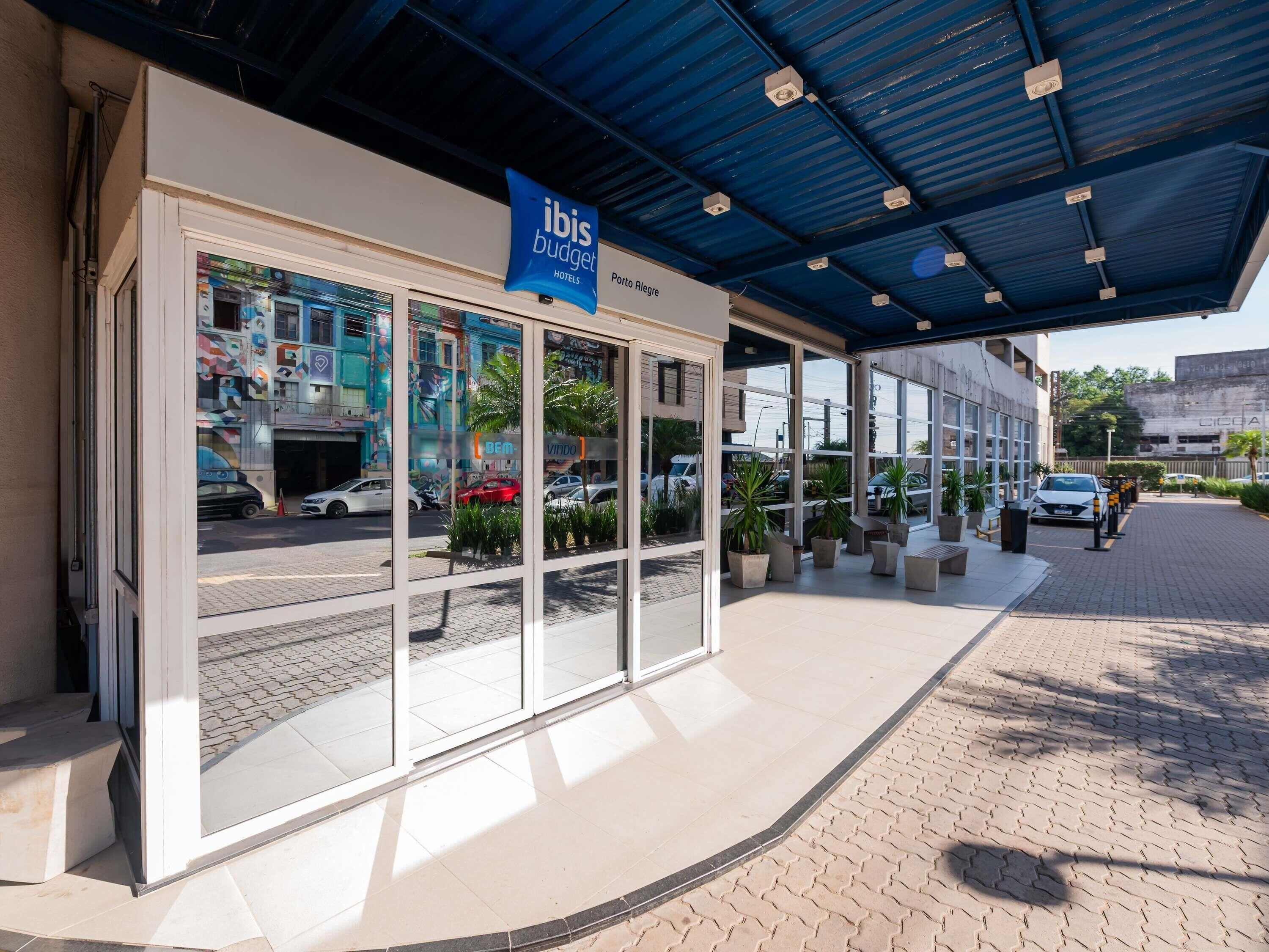 A hotel entrance with a blue awning, glass doors, and a sign for 'ibis budget hotels.'