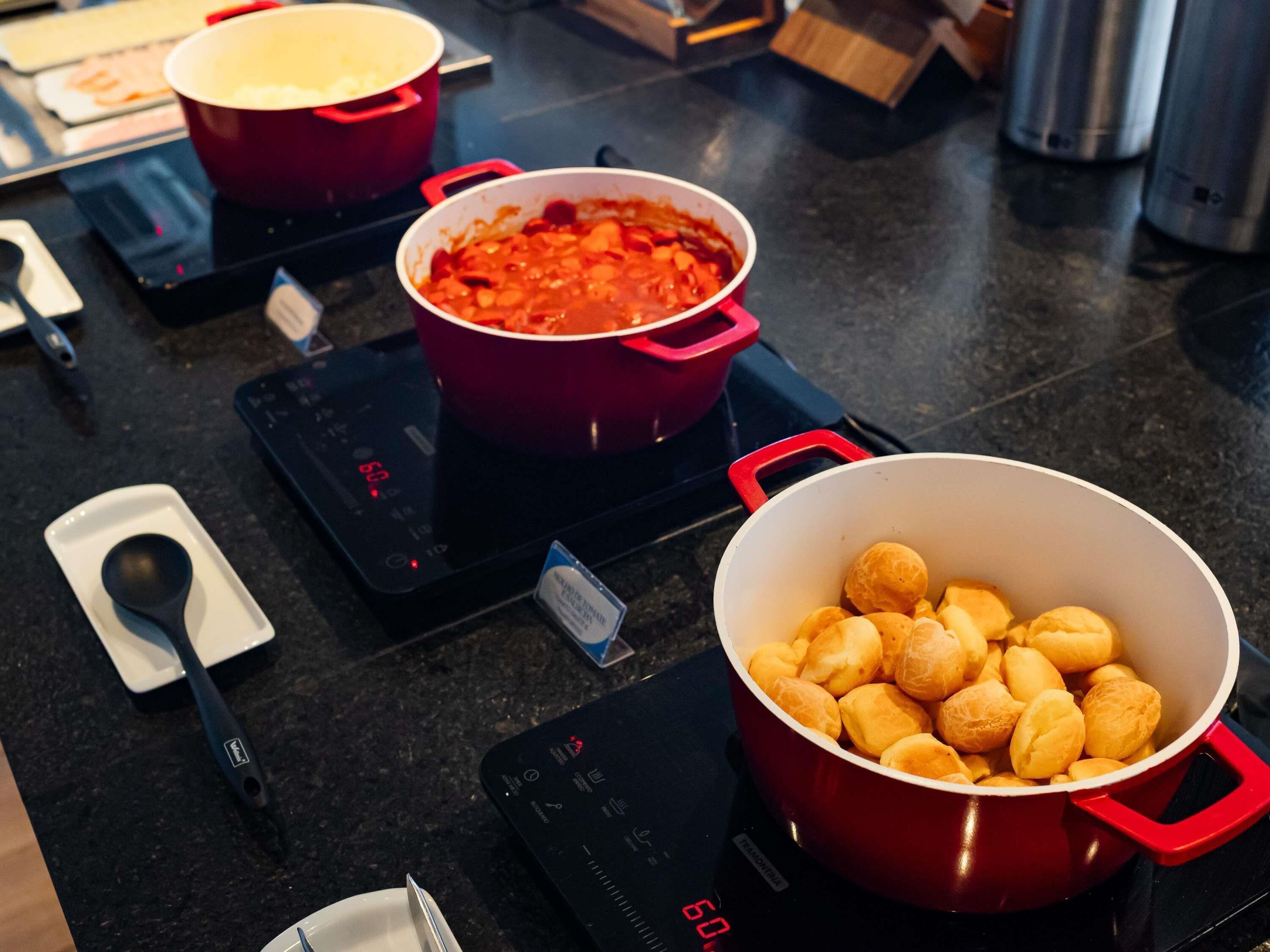 Una cocina con placas de inducción, ollas rojas y un bol de pan.