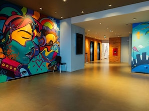 Un hall dâhĂŽtel agrĂ©mentĂ© de peintures murales colorĂ©es, dotĂ© dâun design moderne et offrant un espace propre et spacieux.